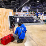 Installers connect a MidNite Solar hybrid inverter to a battery stack at the 2022 Solar Games.